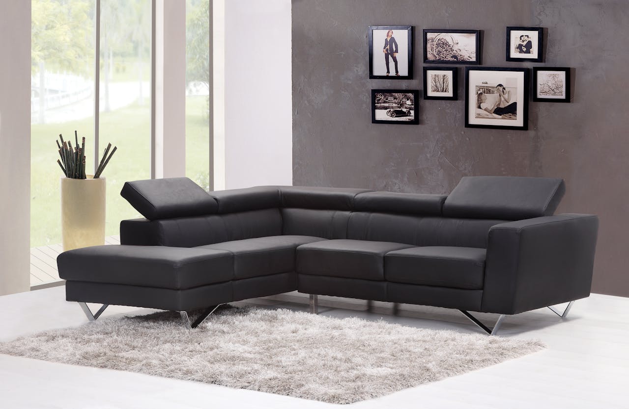 our-story-02 Contemporary living room featuring a sleek black sectional sofa and chic wall art.