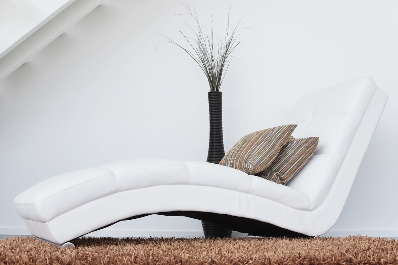 collection-02 Elegant white lounge chair with cushions on plush carpet, perfect for relaxation.